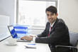 Photo: Portrait of an Indian businessman writing on paper at desk in office Portrait of an Indian businessman writing on paper at desk in office