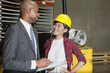 Female industrial worker looking at male inspector as he writes on clipboard