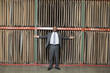 Photo: Portrait of happy African American businessman standing arms outstretched in front of thin veneer sheets Portrait of happy African American businessman standing arms outstretched in front of thin veneer sheets
