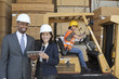 Photo: Happy multiethnic engineers holding tablet PC with female worker driving forklift truck in background Happy multiethnic engineers holding tablet PC with female worker driving forklift truck in background