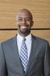 Photo: Portrait of African American businessman smiling with stacked wooden planks in background Portrait of African American businessman smiling with stacked wooden planks in background