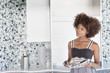 Photo: Young African American woman looking at designed wall as she holds design swatches Young African American woman looking at designed wall as she holds design swatches