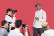Paparazzi taking photographs of male actor over red background