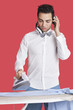 Man ironing cloth while listening music over red background