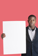 Portrait of a young man holding blank cardboard over pink background
