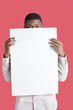 Photo : Portrait of a young man holding blank cardboard in front of face over pink background Portrait of a young man holding blank cardboard in front of face over pink background