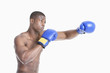 Photo: Young African American boxer boxing over gray background Young African American boxer boxing over gray background