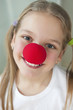 Foto: Close-up portrait of a happy girl with red clown nose Close-up portrait of a happy girl with red clown nose