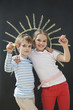 Photo : Portrait of happy siblings holding chalks against blackboard Portrait of happy siblings holding chalks against blackboard