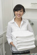 Portrait of young female housekeeper holding clean white folded towels