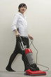 Full length of young female housekeeper vacuuming