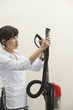 Photo: Female housekeeper holding vacuum cleaner pipe against gray background Female housekeeper holding vacuum cleaner pipe against gray background