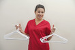 Foto: Portrait of female housekeeper holding white plastic hangers against gray background Portrait of female housekeeper holding white plastic hangers against gray background