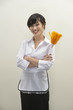 Portrait of female housekeeper holding feather duster against gray background