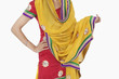 Photo: Midsection of woman in traditional wear standing with hand on hip over white background Midsection of woman in traditional wear standing with hand on hip over white background
