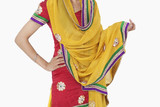 Photo: Midsection of woman in traditional wear standing with hand on hip over white background Midsection of woman in traditional wear standing with hand on hip over white background