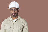 Photo: Portrait of happy young construction worker with hardhat over brown background Portrait of happy young construction worker with hardhat over brown background