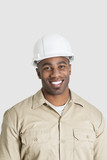 Photo: Portrait of happy young African male construction worker over gray background Portrait of happy young African male construction worker over gray background