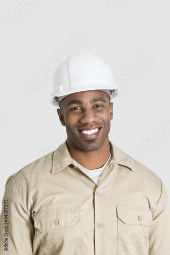 Photo: Portrait of happy young African male construction worker over gray background Portrait of happy young African male construction worker over gray background