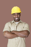 Photo: Portrait of cheerful young African construction worker over brown background Portrait of cheerful young African construction worker over brown background