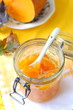 Foto: A glass jar of a fresh pumpkin jam on yellow background A glass jar of a fresh pumpkin jam on yellow background
