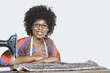 Photo: Portrait of an African American female fashion designer with sewing machine and cloth over gray background Portrait of an African American female fashion designer with sewing machine and cloth over gray background