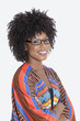Photo: Portrait of young woman in African print attire standing hands folded over gray background Portrait of young woman in African print attire standing hands folded over gray background
