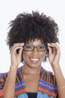 Photo: Portrait of young woman in African print attire wearing glasses over gray background Portrait of young woman in African print attire wearing glasses over gray background