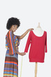 Photo: Portrait of African American female designer measuring a red tunic over gray background Portrait of African American female designer measuring a red tunic over gray background