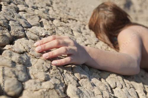 Photo: Woman lying on cracked land with focus on hand Woman lying on cracked land with focus on hand