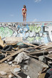 Young woman in bikini standing on graffiti wall with garbage in foreground