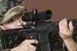 Photo: Young female US Marine Corps soldier aiming M4 assault rifle over brown background Young female US Marine Corps soldier aiming M4 assault rifle over brown background