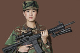 Photo: Portrait of beautiful young US Marine Corps soldier with M4 assault rifle over brown background Portrait of beautiful young US Marine Corps soldier with M4 assault rifle over brown background