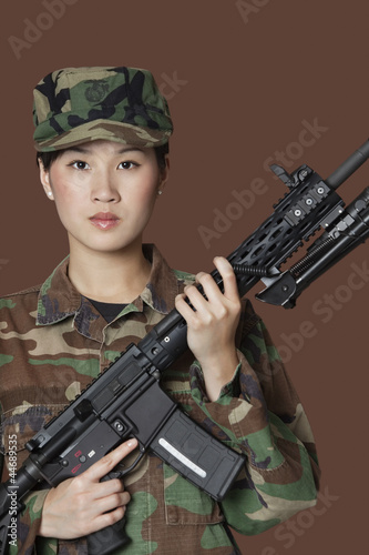 Photo: Portrait of beautiful young US Marine Corps soldier with M4 assault rifle over brown background Portrait of beautiful young US Marine Corps soldier with M4 assault rifle over brown background