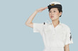 Beautiful young US Navy officer saluting over light blue background