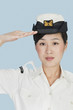 Foto: Portrait of a beautiful young US Navy officer saluting over light blue background Portrait of a beautiful young US Navy officer saluting over light blue background