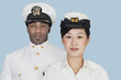 Portrait of two multi-ethnic US Navy officers over light blue background
