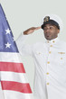 Foto: Portrait of a young US Navy officer saluting American flag over gray background Portrait of a young US Navy officer saluting American flag over gray background