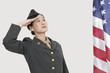 Foto: Serious female US military officer saluting American flag over gray background Serious female US military officer saluting American flag over gray background