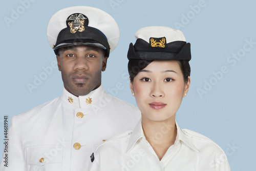 Photo: Portrait of two multi-ethnic US Navy officers over light blue background Portrait of two multi-ethnic US Navy officers over light blue background