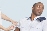 Photo: Young military man looking away as being injected by nurse over light blue background Young military man looking away as being injected by nurse over light blue background