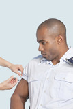 Photo: Young military man getting an injection from nurse over light blue background Young military man getting an injection from nurse over light blue background