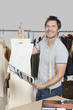 Portrait of male dressmaker holding sewing pattern, sketch and design draft