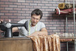 Mature male dressmaker stitching cloth on sewing machine