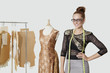 Photo: Portrait of beautiful female fashion designer standing with hand on hip over gray background Portrait of beautiful female fashion designer standing with hand on hip over gray background