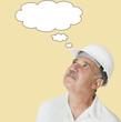 Photo: Senior construction worker with hardhat looking up over yellow background Senior construction worker with hardhat looking up over yellow background