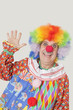 Foto: Portrait of cheerful senior male clown waving hand over gray background Portrait of cheerful senior male clown waving hand over gray background