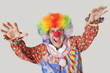 Foto: Portrait of funny clown with arms raised and mouth open against colored background Portrait of funny clown with arms raised and mouth open against colored background