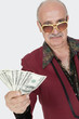 Foto: Portrait of senior man showing US banknotes against gray background Portrait of senior man showing US banknotes against gray background