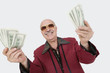 Photo: Portrait of cheerful senior man showing US banknotes against gray background Portrait of cheerful senior man showing US banknotes against gray background
